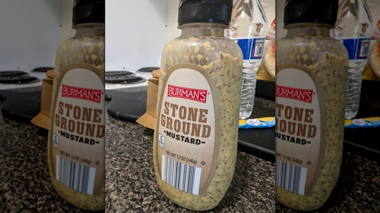 A partially empty bottle of Burman's stone ground mustard city on a countertop