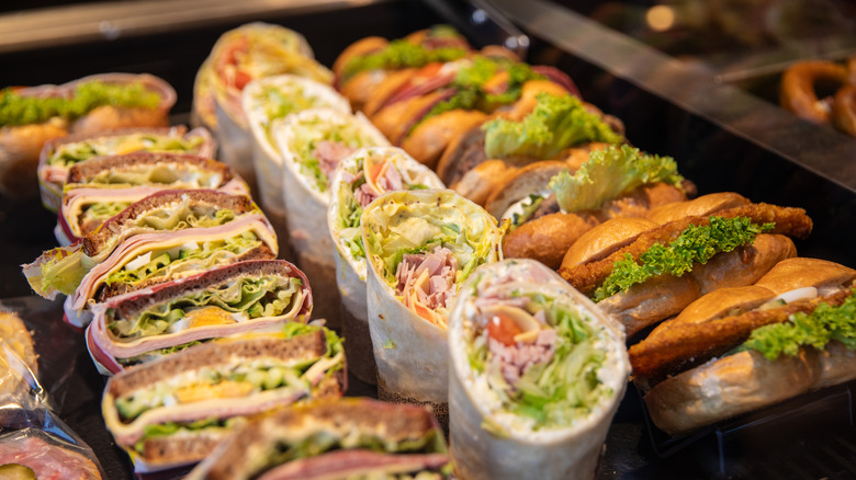A display of different kinds of sandwiches and wraps filled with various meats, vegetables, and cheese
