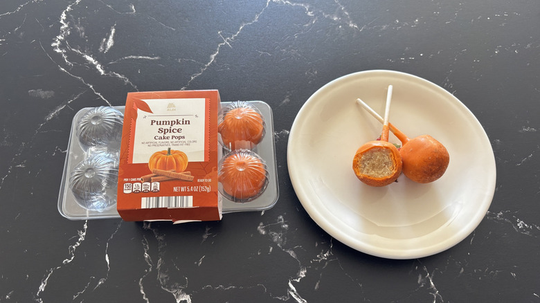 An Aldi Pumpkin Spice Cake Pops container next to the cake pops on a white plate
