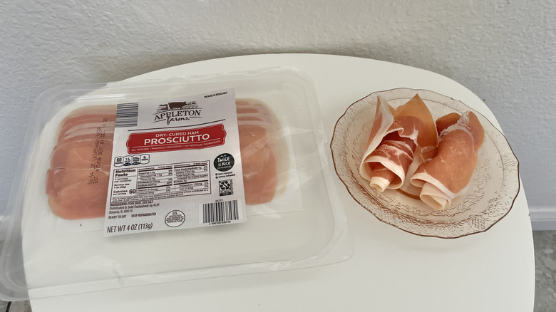 Rolled up pieces of prosciutto on a plate and a plastic packaging