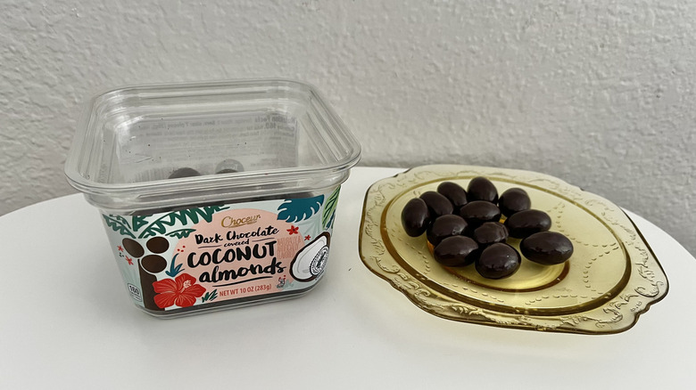 Chocolate covered coconut almonds package with a handful of pieces on a yellow plate