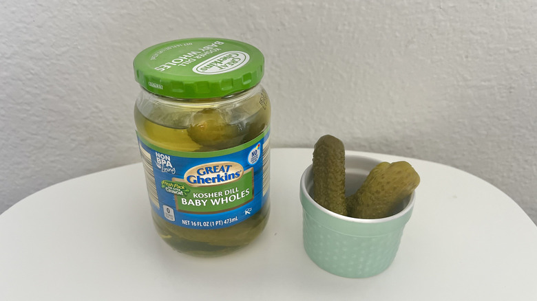 Small baby dill pickles in a jar with some in a separate container