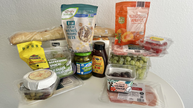 Various Aldi products on a table including nuts, fruit, bread, meat, and cheese