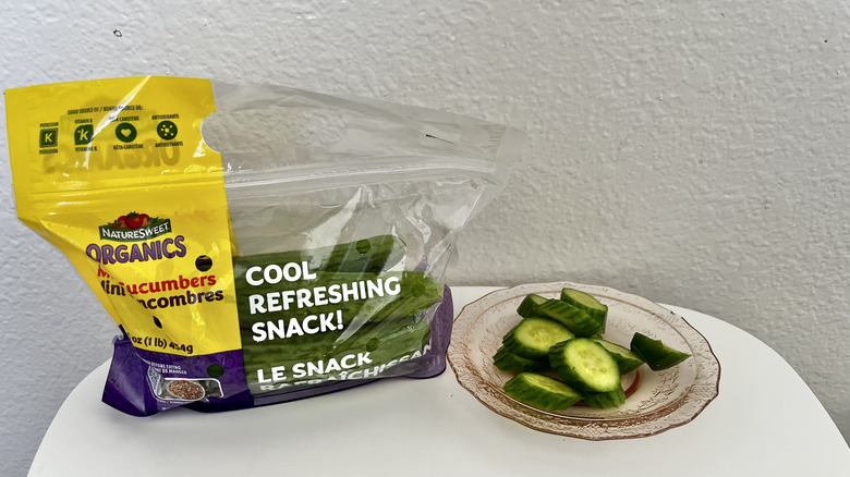 A bag of cut up mini cucumbers with some pieces on a separate plate