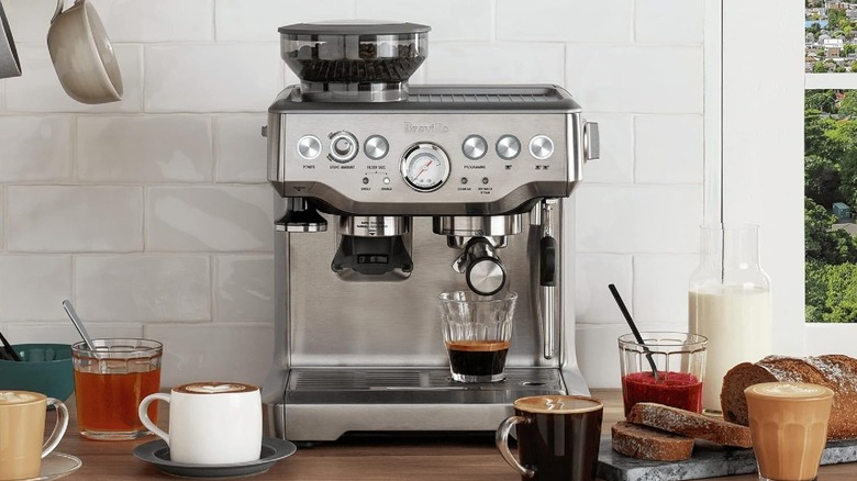 An espresso machine on a kitchen countertop with numerous drinks on the counter