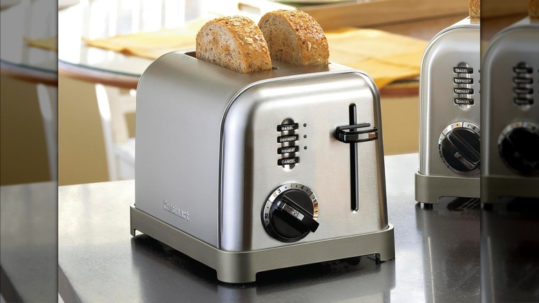 A brushed metal Cuisinart two slice toaster featuring several settings sitting on the countertop with popped toast inside