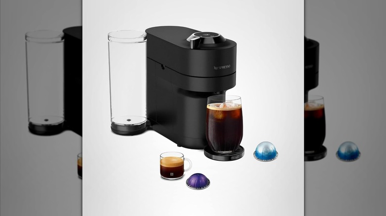 White and black Nespresso coffee machine with coffee drinks and pods arranged around it