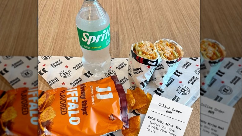 A Jimmy John's sub cut in half, a bag of chips, and a Sprite