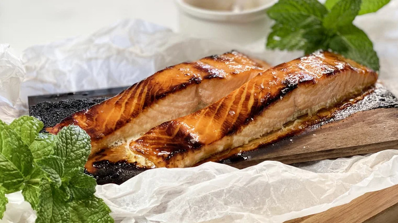 Two glazed and charred salmon pieces on a maple plant