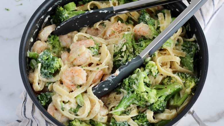 A black bowl filled with shrimp alfredo and broccoli
