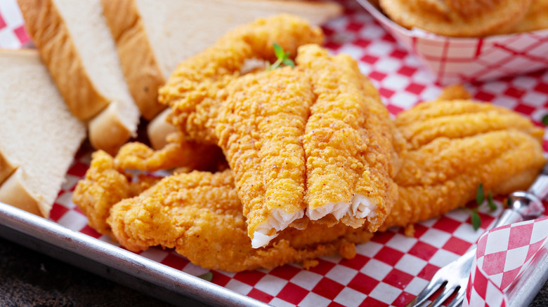 Fried fish with slices of bread on metal platter