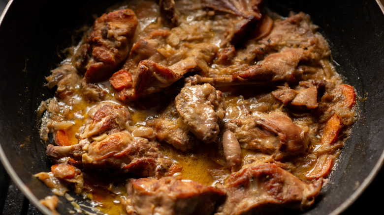 Rabbit stewed with onions and carrots in pan