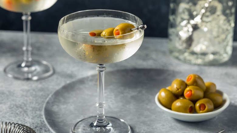 Dirty martini beside olives