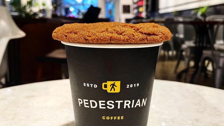 Brown butter cookie on top of a Pedestrian Coffee takeaway cup