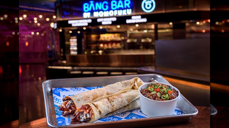 Two wraps on tray with side bowl in front of the storefront for the Bang Bar