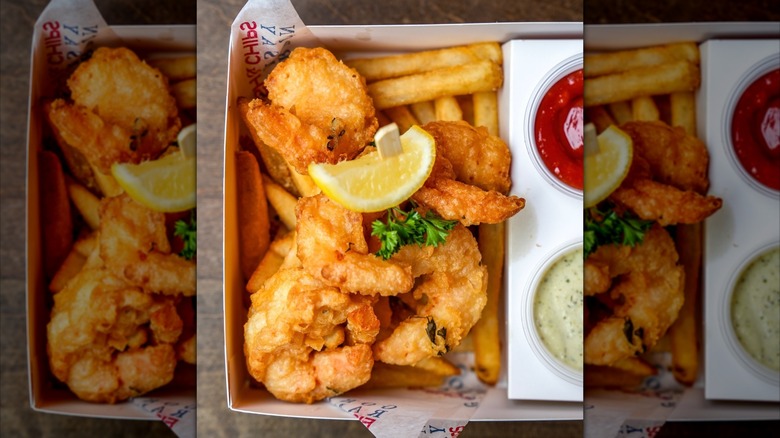 Shrimp basket with lemon, fries, and sauces on the side