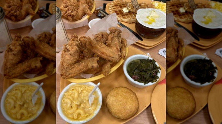 Table full of assorted dishes including fried chicken, waffles, collard greens,and cornbread