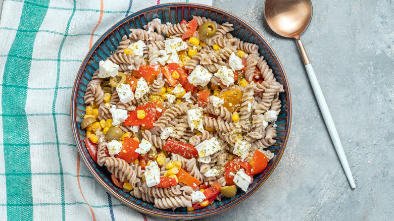 Pasta salad with tomatoes, red pepper, feta cheese, and olives.