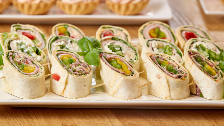 Pinwheel sandwiches ordered in three rows of five on a white plate.