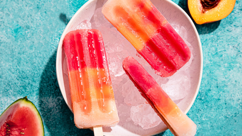 Popsicles made with watermelon and peach over a bowl of ice.