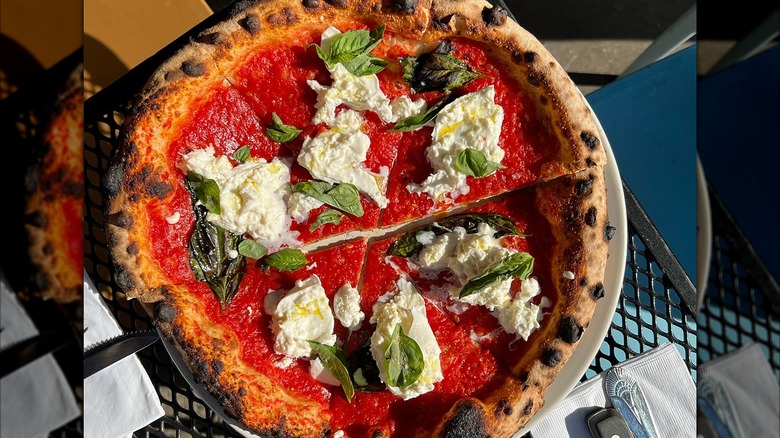 Burrata pizza with basil on a table