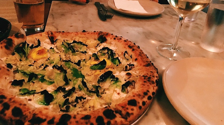 Egg and brussel sprout pizza on a white table