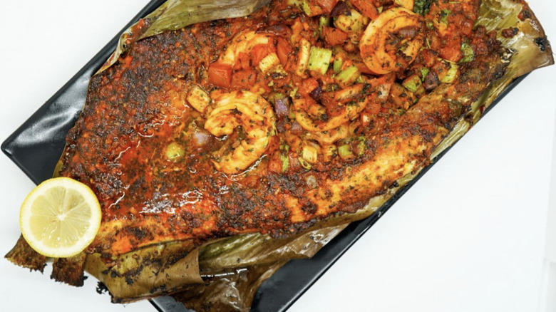 seasoned fish with grilled shrimp on top.