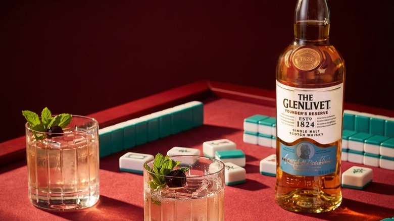 A bottle of The Glenlivet Founder's Reserve next to a couple of cocktails and mahjong pieces