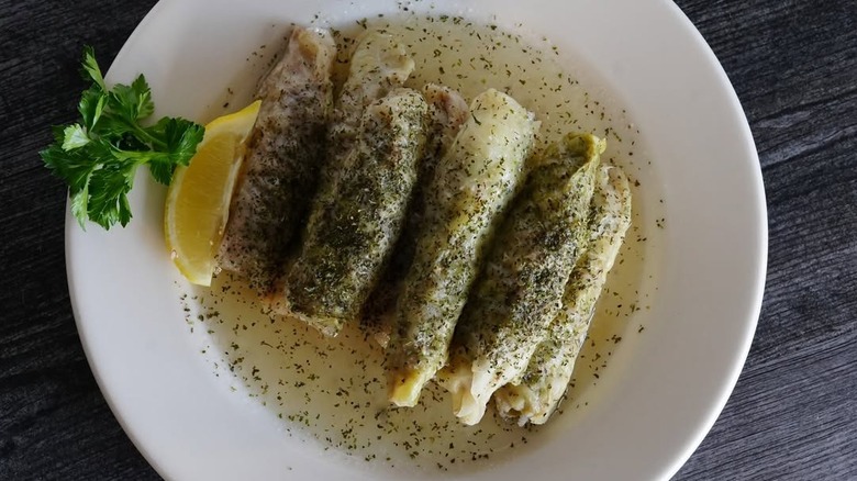 Stuffed cabbage rolls sprinkled with dried mint with lemon wedge on white plate