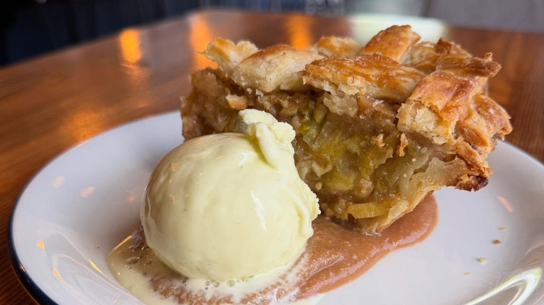 Slice of green tomato pie and scoop of vanilla ice cream scoop on white plate