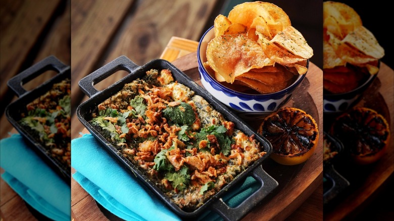 Spinach dip in an iron pan and bowl of chips