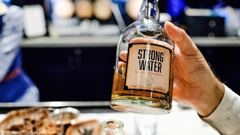 Holding a bottle of Strong Water rum