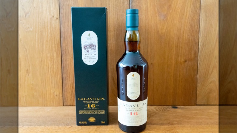 Bottle of Lagavulin 16 next to its box on wooden table