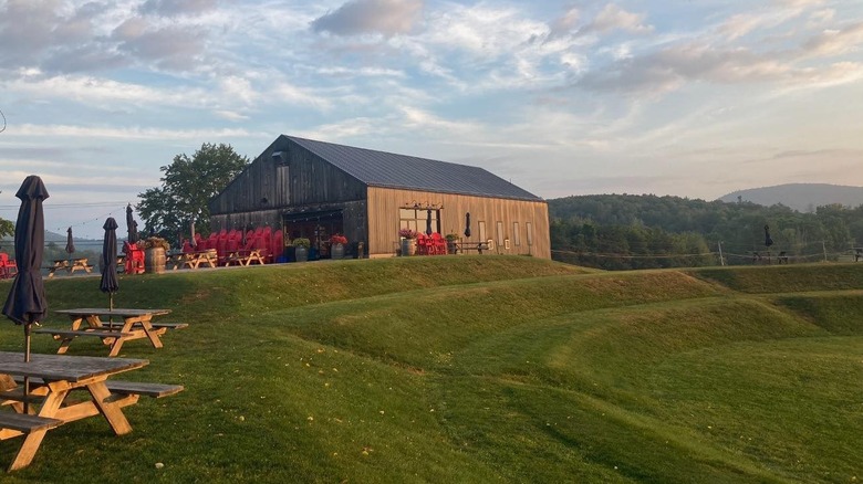 A farmhouse winery on a hill surrounded by picnic tables