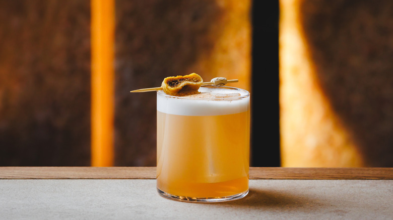 Classic amaretto sour in a tumbler with a fig garnish