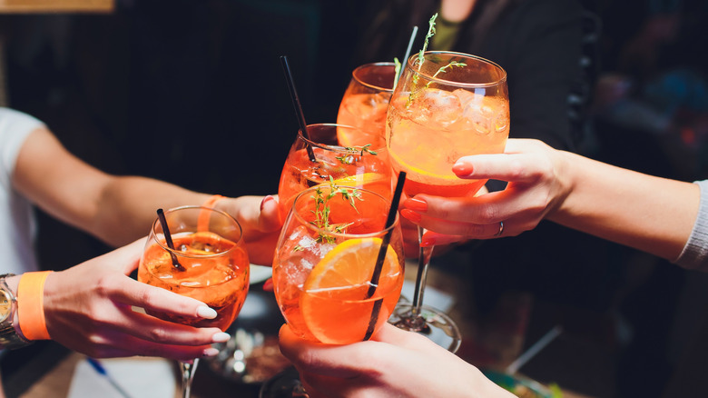 A group of people clinking glasses filled with Aperol Spritz