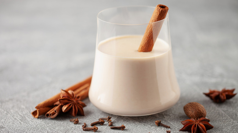 A glass of coquito with cinnamon sticks and star anise garnishes