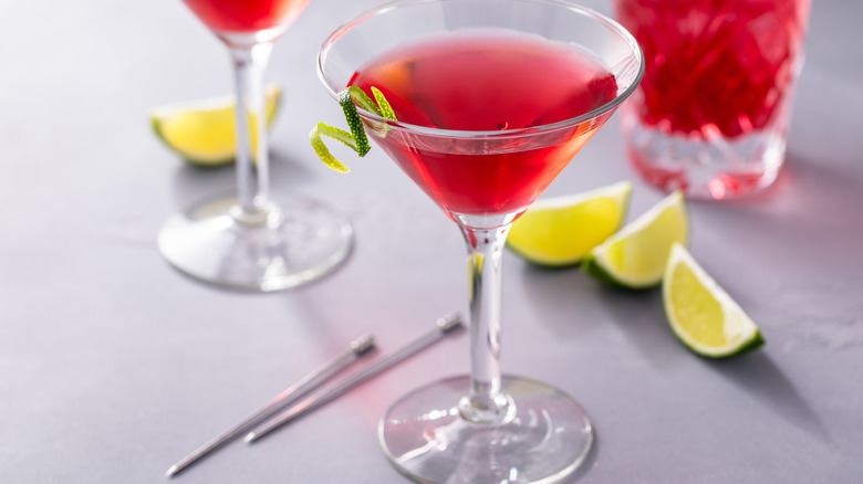 A cosmopolitan cocktail with lime wedges on the side