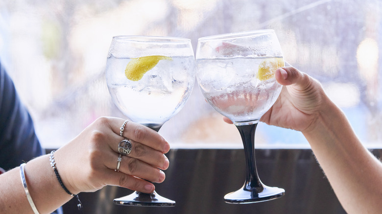 Two people clinking with glasses of gin and tonic