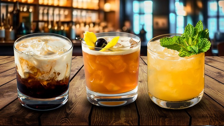 A composite image of three mixed cocktails in tumblers on a wooden table