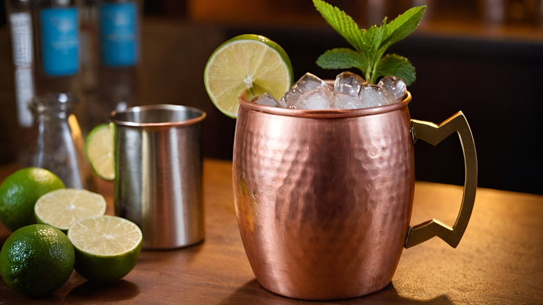 A Moscow Mule in a copper cup with limes on the side