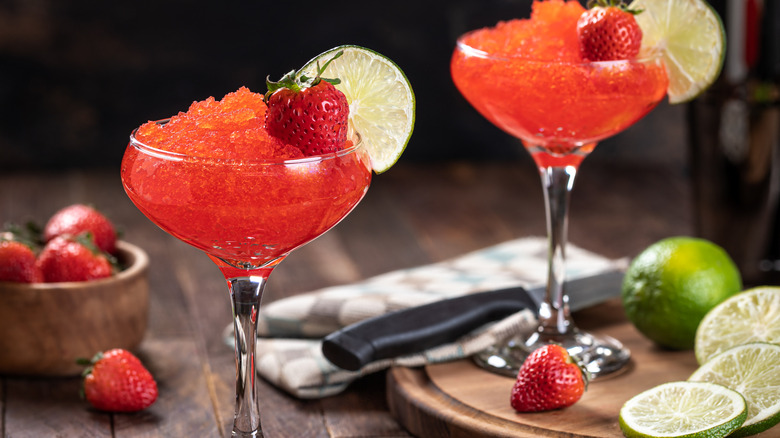 Two strawberry daquiris garnished with strawberries and lime