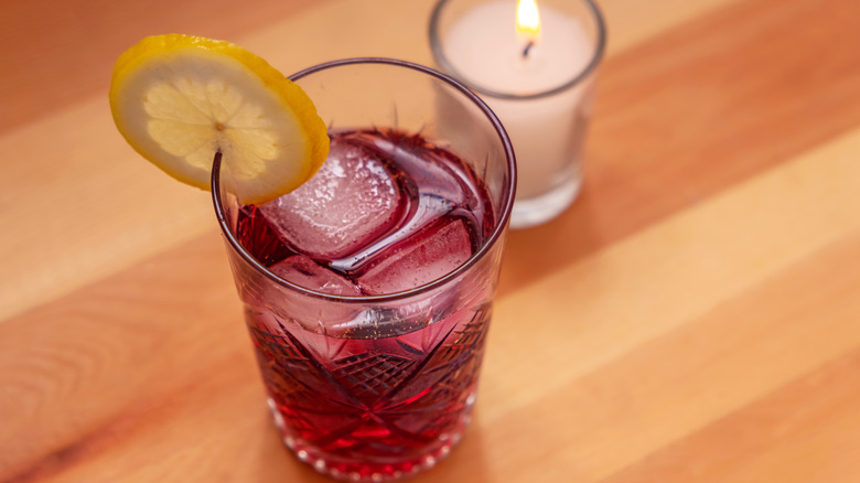A glass of tinto de verano with a candle alongside it