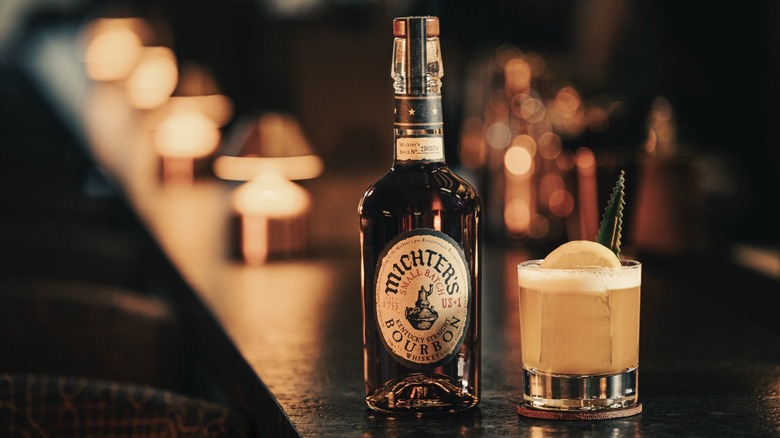 A bottle of Michter's Small Batch Bourbon shown on a bar next to a cocktail