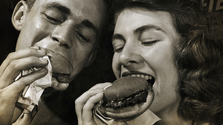 Black and white close up of couple enjoying fast food burgers