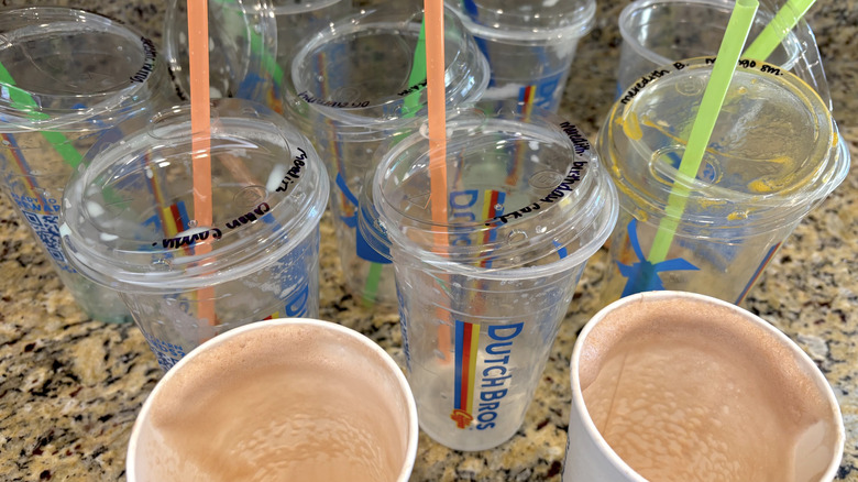 A variety of Dutch Bros empty cardboard and plastic cups on marble countertop