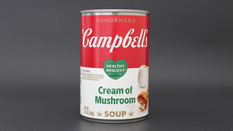A can of Campbell's cream of mushroom soup with a dark gray background.