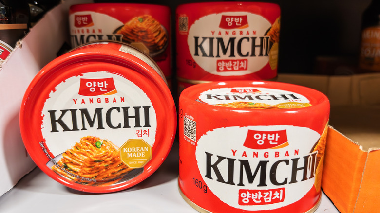 Four cans of kimchi on a shelf.