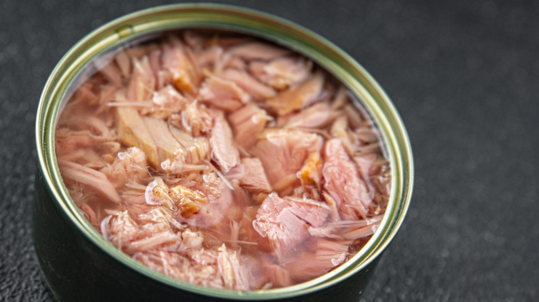 A can of flaky tuna with a dark gray background.