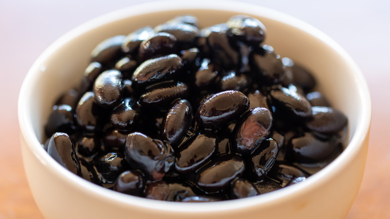 White bowl of black beans with a black background